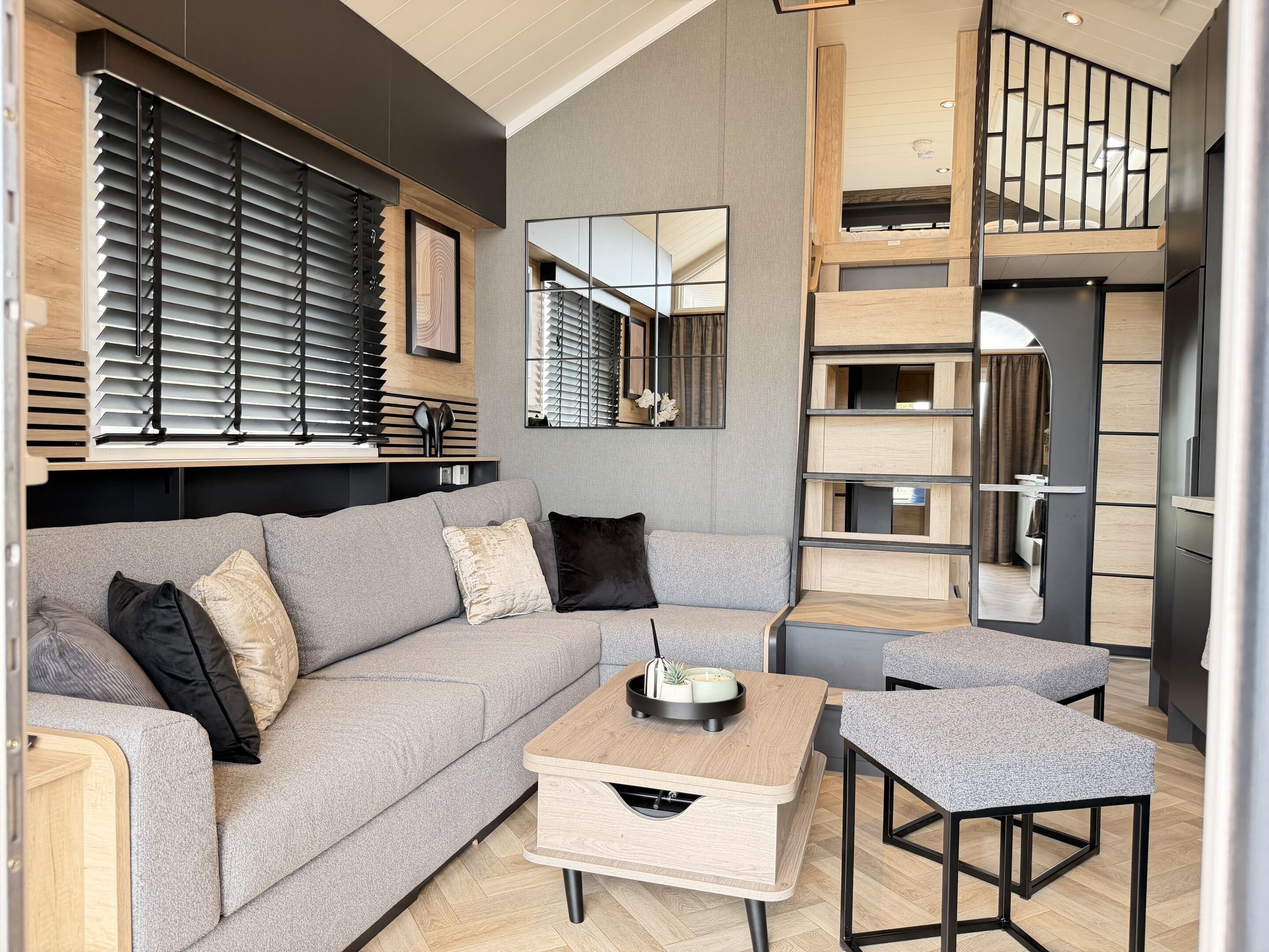 A modern living room with a grey sofa, a wooden coffee table, and a mirror.