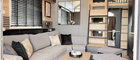 A modern living room with a grey sofa, a wooden coffee table, and a mirror.