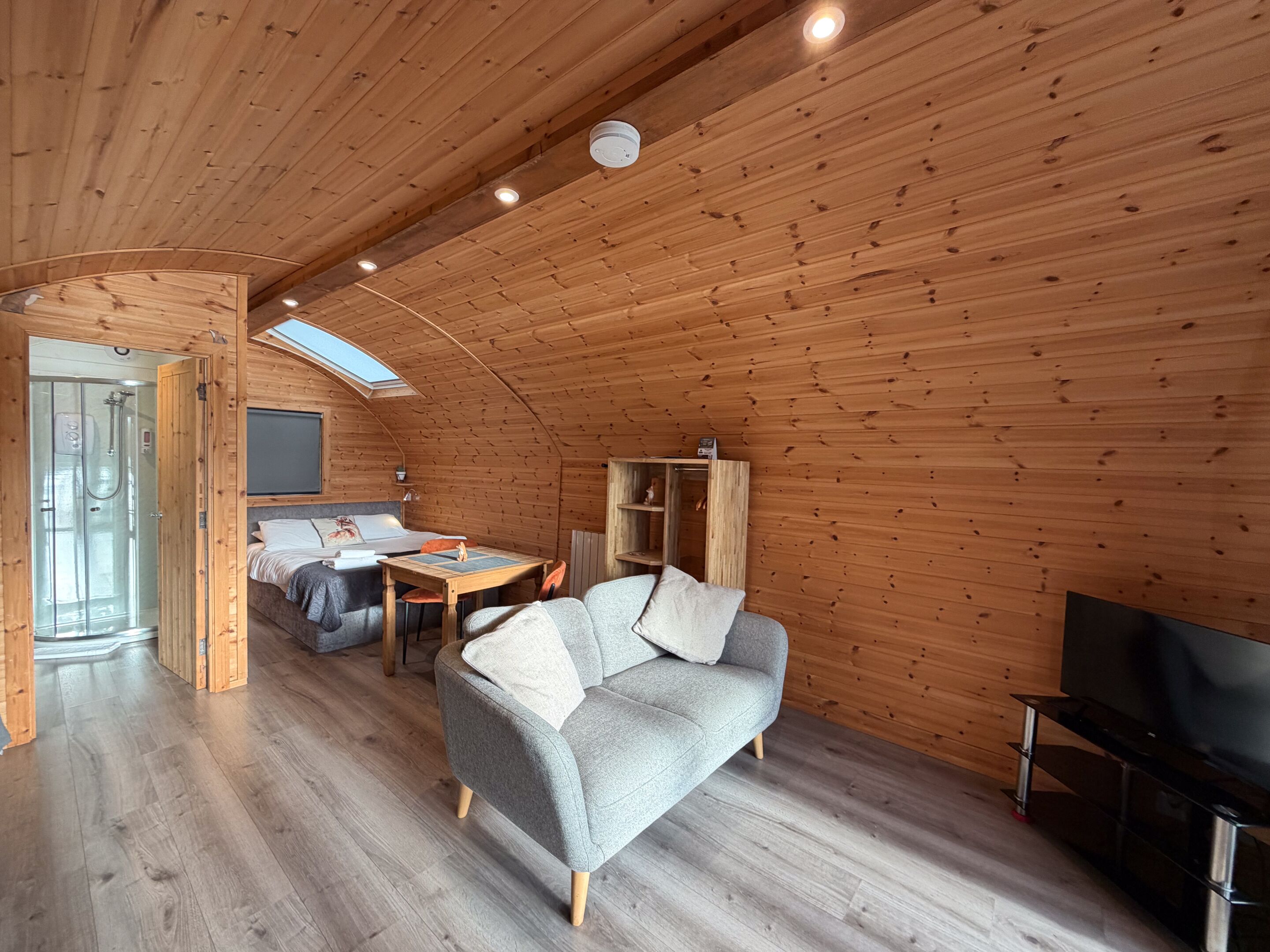 A cozy cabin with a loft bedroom, a dining area, and a living room with a sofa and TV.