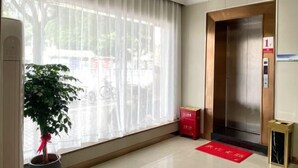 A hotel lobby with a large window, an elevator, a potted plant, and a red mat on the floor. - Sanmen Longyoujia Boutique Hotel (Sanmen)