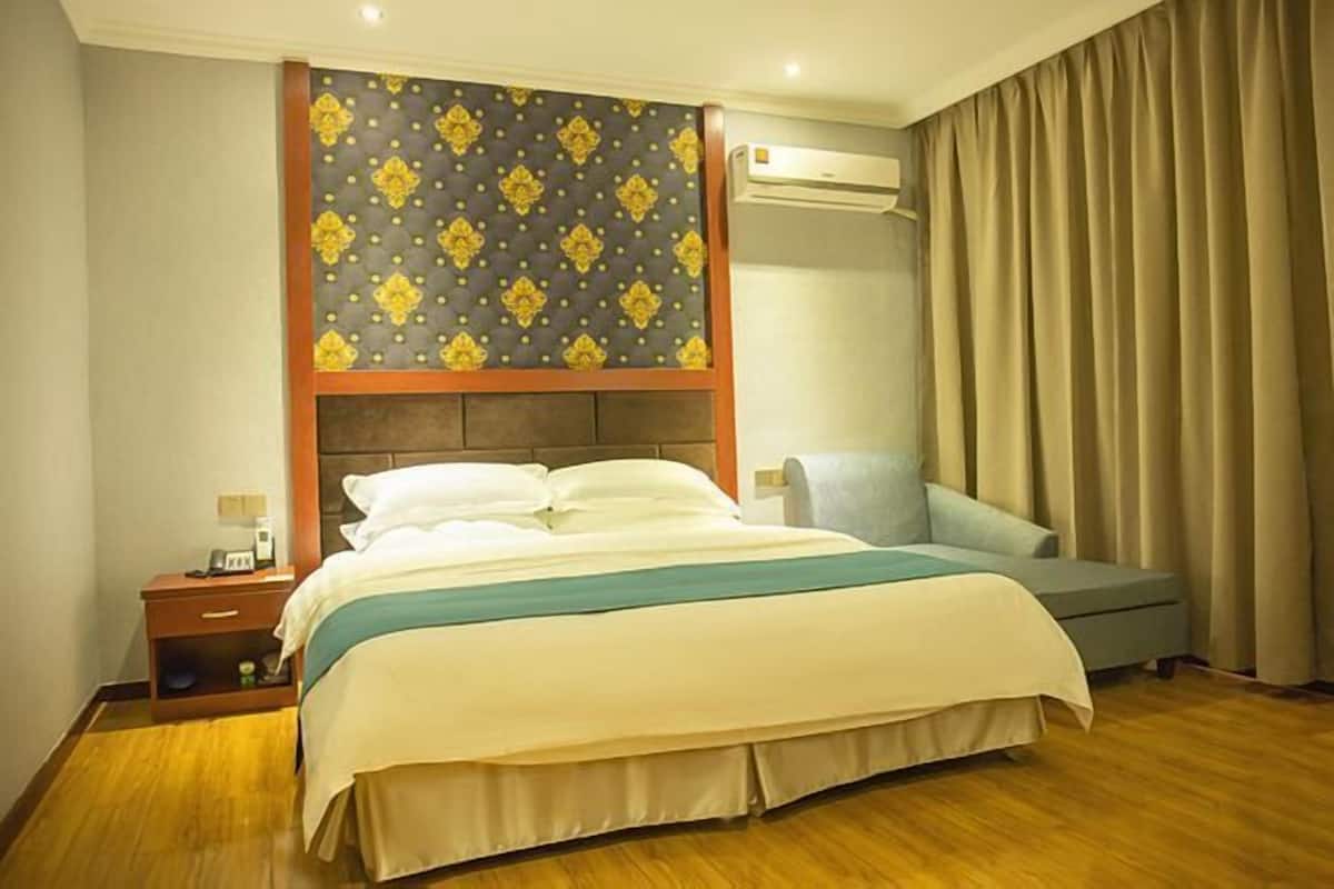 A hotel room with a bed, bedside table, and a sofa.