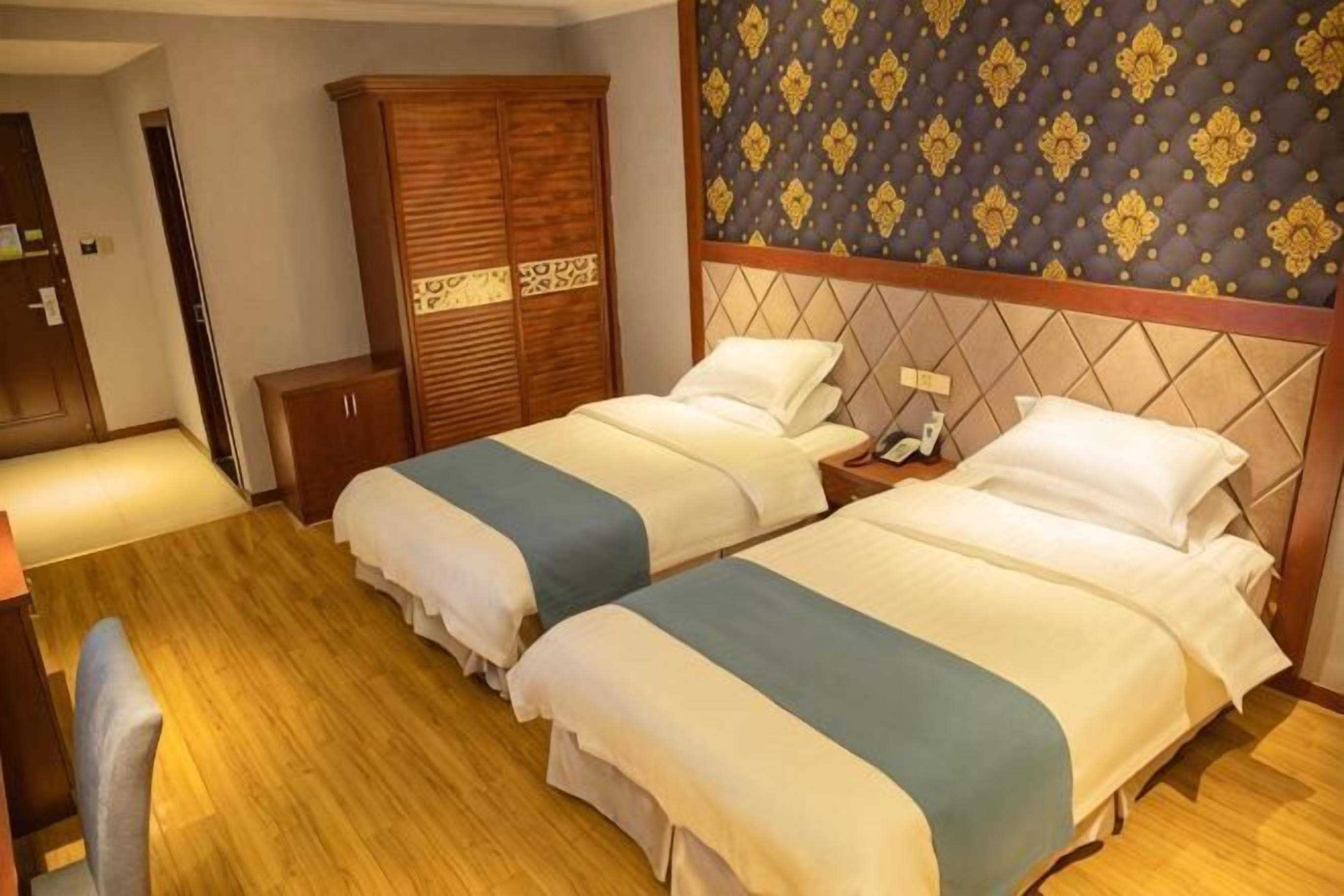 Ein Hotelzimmer mit zwei Betten, einem Holzschrank, einem Schreibtisch und einer Wand mit Muster.