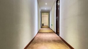 A long, narrow hallway with carpeted floors and white walls, leading to a door at the end. - Sanmen Longyoujia Boutique Hotel (Sanmen)