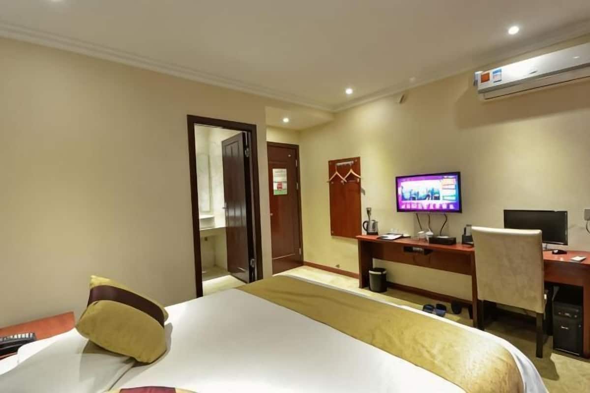 A hotel room with a bed, a desk with a computer, a television, and a mirror.