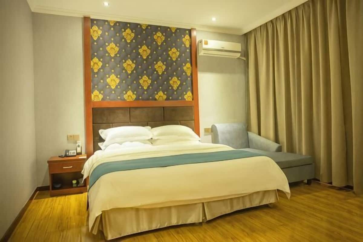 A hotel room with a bed, bedside table, and a large window with curtains.