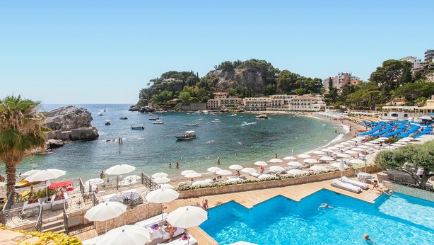 Un resort costero con piscina, playa y barcos en el agua.
