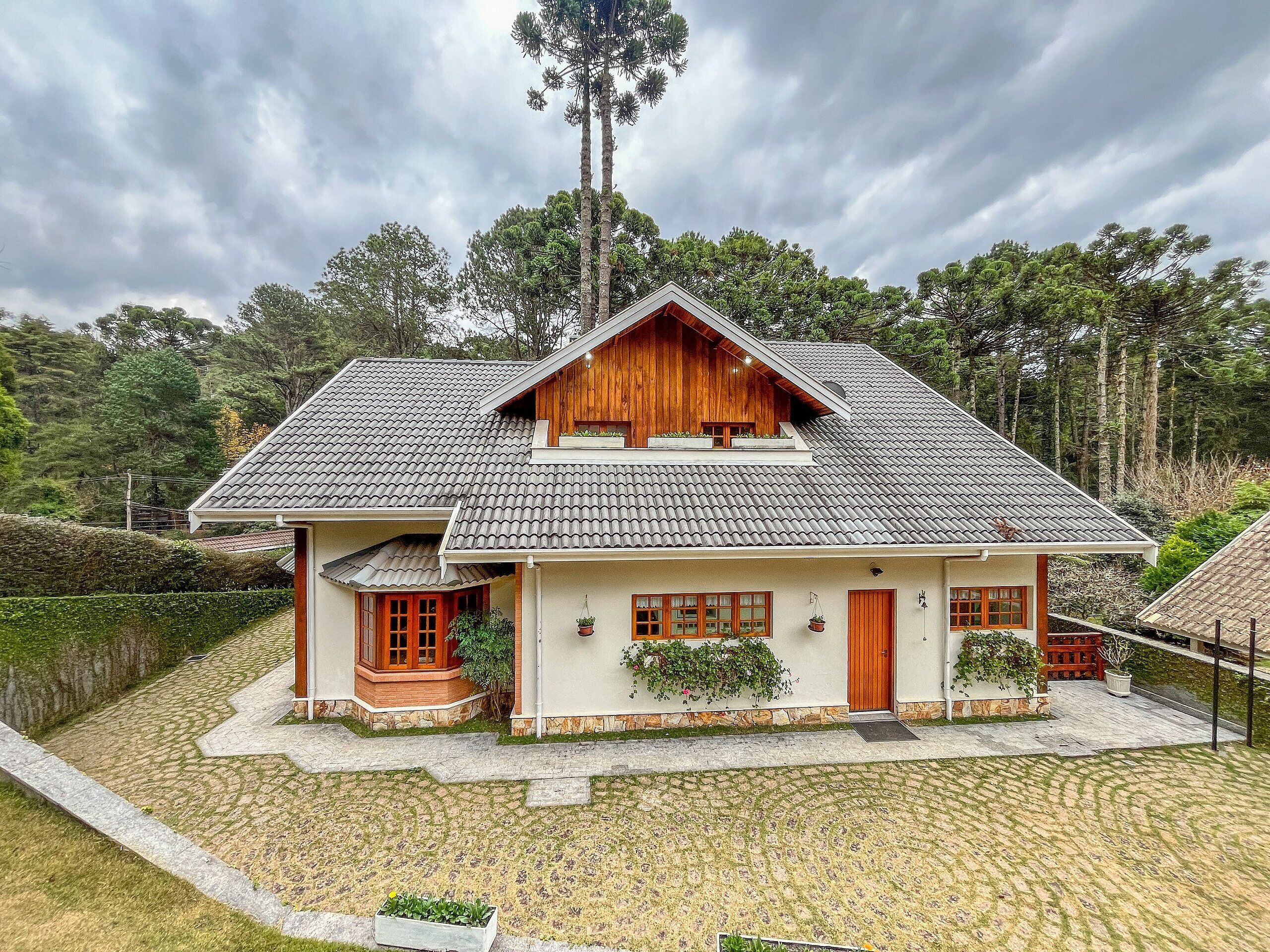A two-story house with a tiled roof, wooden exterior, and a small porch with potted plants.