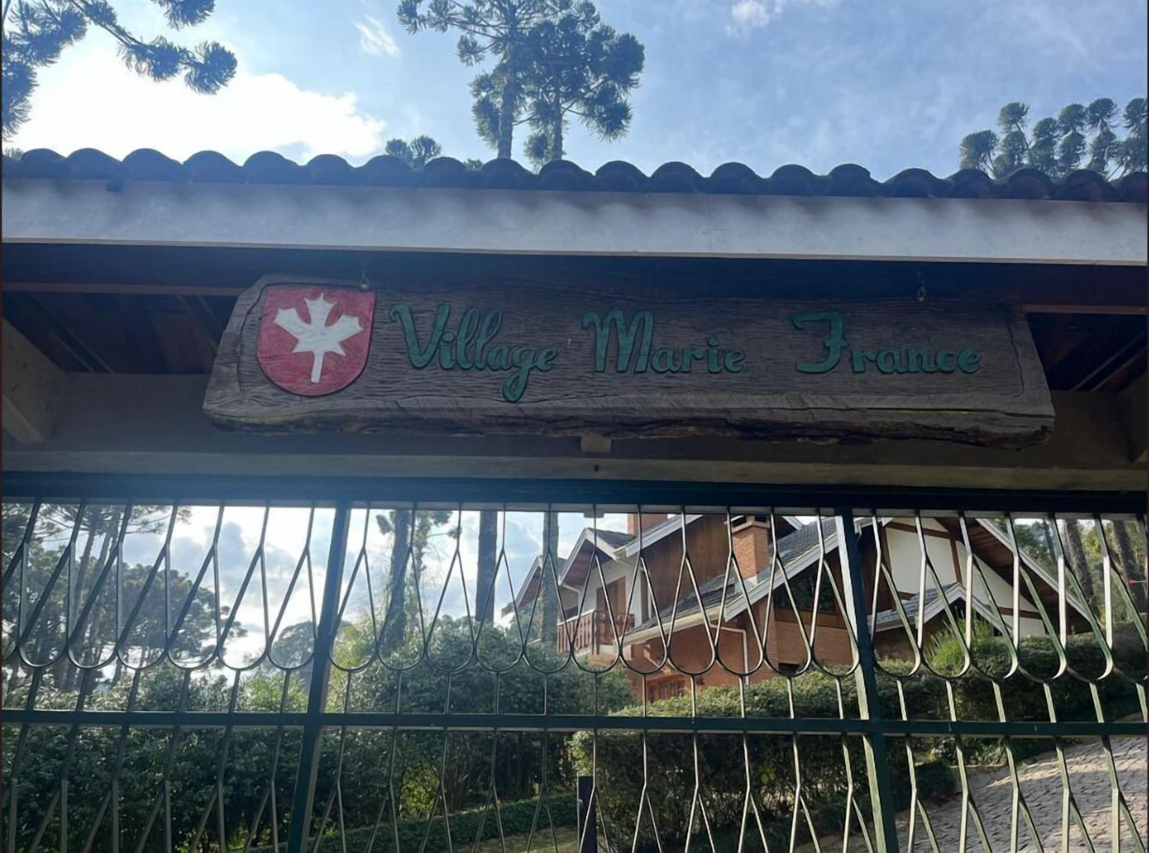 A sign with 'Village Marie France' and a red shield emblem.