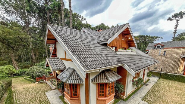 A two-story house with a tiled roof, a stone pathway, and a garden. - Casa Horto Village (Campos do Jordão)