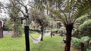 A garden with a hammock, a bench, and a lamppost. - Casa Horto Village (Campos do Jordão)