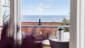 A balcony with a view of the sea, a tiled roof, and a chimney. - Gudhjem Søpark Lejl. 51 (Gudhjem)