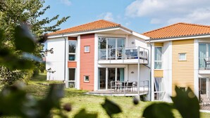A modern two-story residential building with a balcony and a small outdoor seating area. - Gudhjem Søpark Lejl. 51 (Gudhjem)