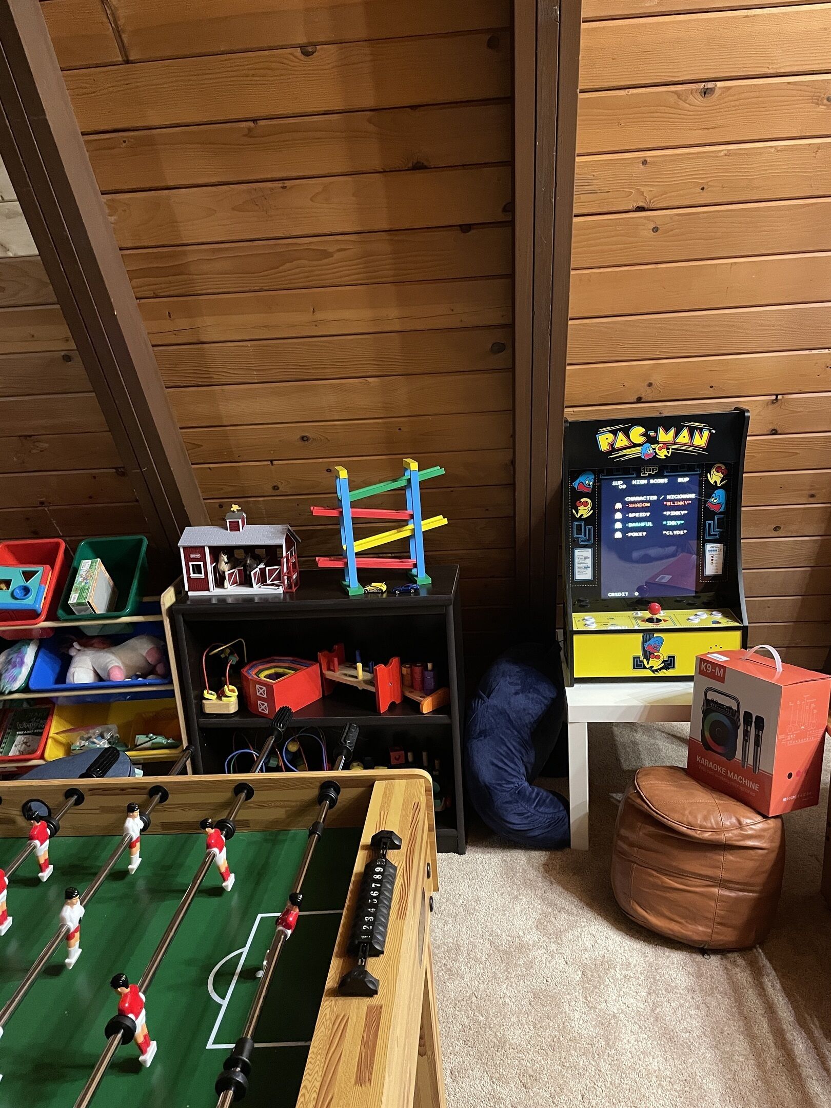 Ett rum med ett fotbollsspel, en Pac-Man-spelautomat och en karaokespelare.