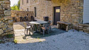 An outdoor patio with stone walls, a table, and chairs.