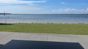 A view of a lake with a grassy area in the foreground and a clear sky.