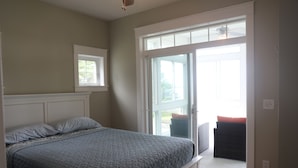 A bedroom with a bed, a window, and a sliding glass door leading to an outdoor area.