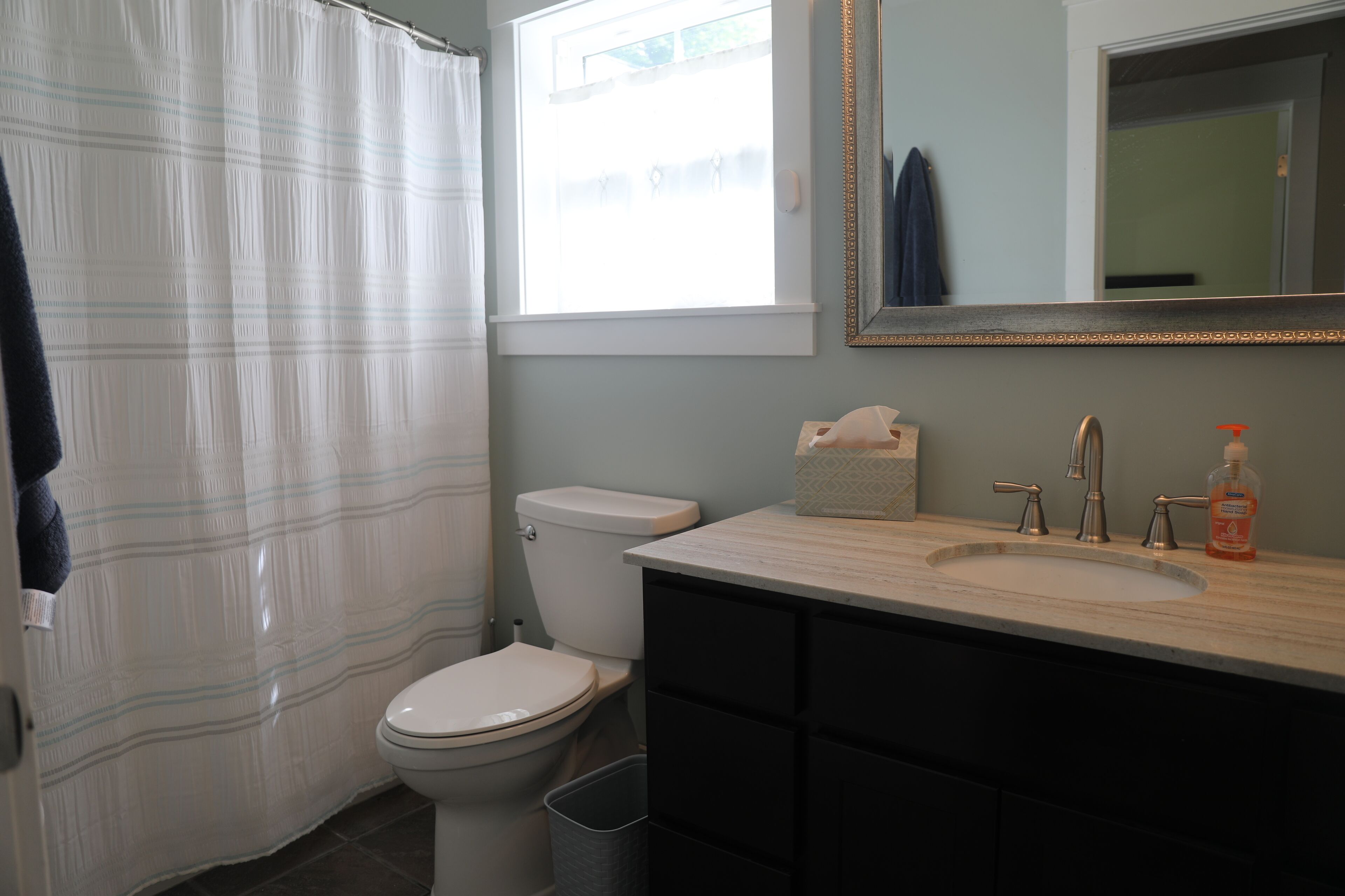 A bathroom with a toilet, sink, and shower curtain.