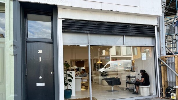 A storefront with a large glass window and a black door with the number 38.
