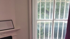 A bedroom with a bed, a desk, and a window.