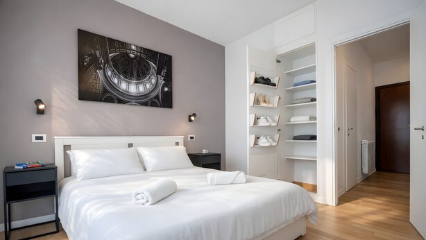 A modern bedroom with a large bed, a built-in wardrobe, and a cityscape artwork on the wall. - Sunny Monteverde Escapes (ROMA)