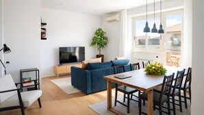 A modern living room with a sofa, dining table, chairs, a TV, and a potted plant. - Sunny Monteverde Escapes (ROMA)