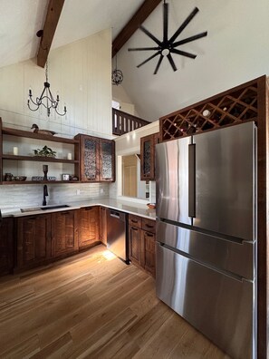 Una cocina moderna con armarios de madera, un refrigerador de acero inoxidable y una araña.