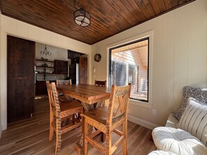 Una mesa de comedor de madera con sillas, una zona de cocina y un ventanal con vistas.