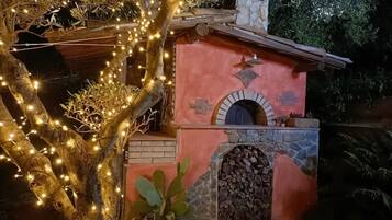 Un bâtiment rustique doté d’une cheminée en pierre, d’une petite entrée en arc de cercle et d’une structure en bois sur le toit.