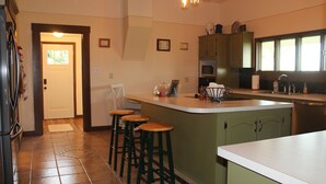 A kitchen with a central island, bar stools, a refrigerator, and a microwave. - The Farm House - Quiet Country Retreat! Great for Any Season - Pet Friendly! (Osborn)