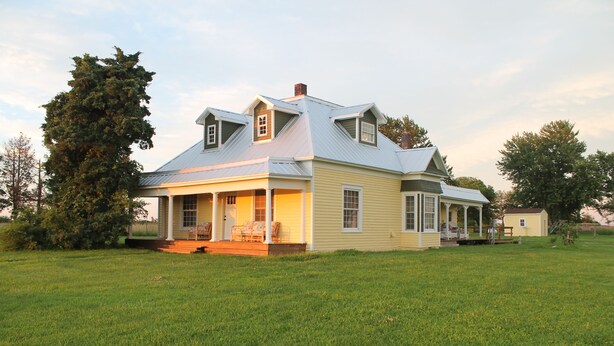 A two-story house with a porch, a covered front porch area, and a small attached garage. - The Farm House - Quiet Country Retreat! Great for Any Season - Pet Friendly! (Osborn)