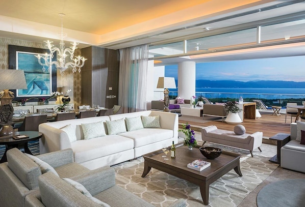 A spacious living area with a white sofa, a coffee table, and a view of the sea.