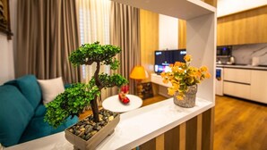Ein modernes Wohnzimmer mit einer Couch, einem kleinen Tisch mit Lampe und einem dekorativen Regal mit Pflanzen und Blumen.