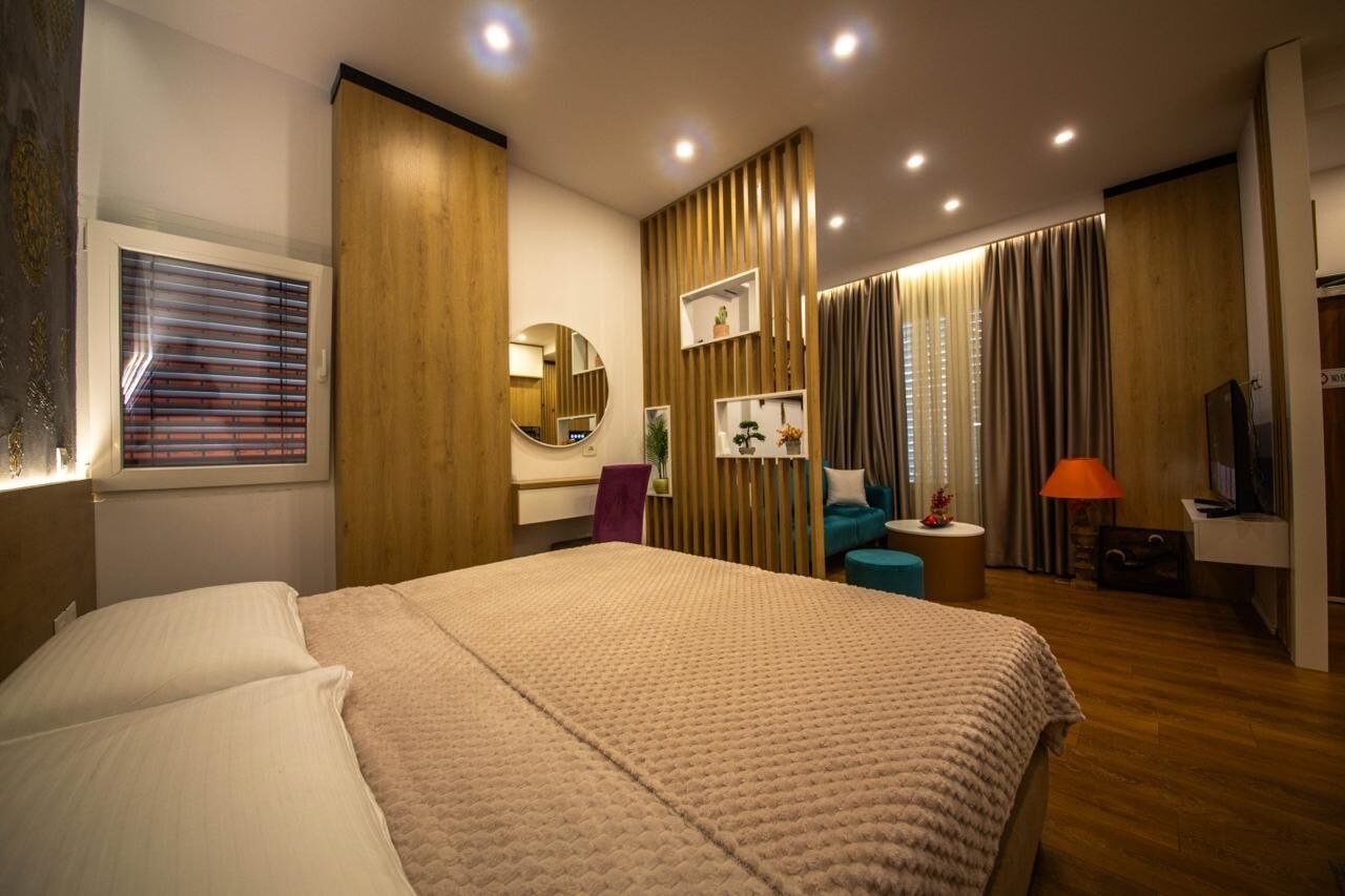 Een moderne hotelkamer met een groot bed, een bureau, een stoel, een televisie en een badkamer met douche en toilet.