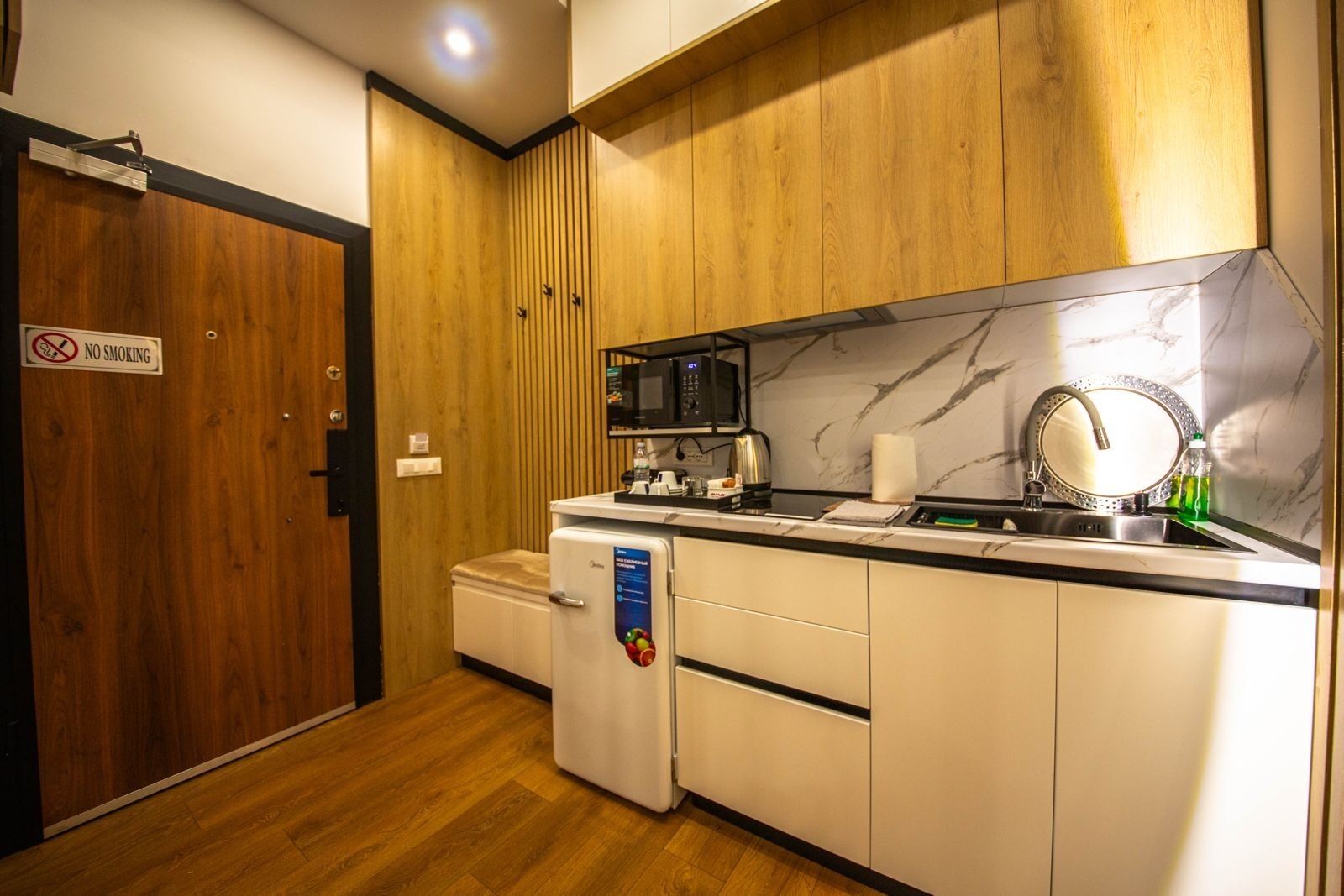 A compact kitchen with a microwave, kettle, and sink.