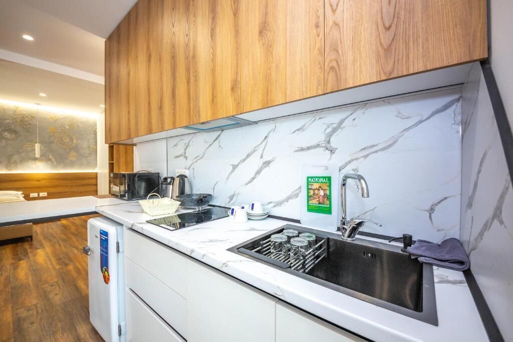A modern kitchen with wooden cabinets, a marble backsplash, and a sink with a soap dispenser.