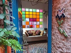 A cozy room with a colorful stained glass window, a cushioned bench, and a textured wall. - Bella Casa 110m2 - Centro - Patio - BBQ

 (Rosario)
