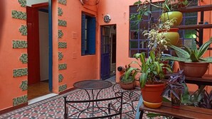 A courtyard with a tiled floor, a round metal table, and several potted plants.