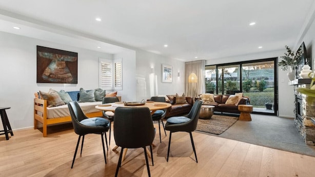 A modern living room with a dining area, a sofa set, and a fireplace. - Wanaka Station Apartment (Wānaka)
