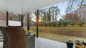 A covered outdoor area with wicker furniture and potted plants. - Wanaka Station Apartment (Wānaka)