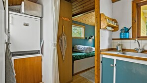 Eine kleine Küche mit Kühlschrank, Spüle und einem Fenster über dem Bett.