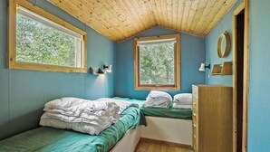 Ein Schlafzimmer mit zwei Betten, Holzbalkendecke und großen Fenstern.