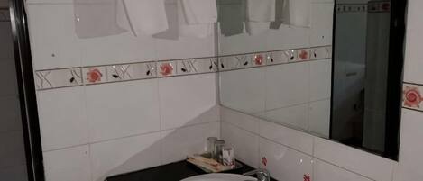 A bathroom with a white sink, a mirror, and a towel rack.
