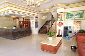 A hotel lobby with a reception desk, a staircase, and a seating area. - Menglian Kailei Hotel (Menglian)