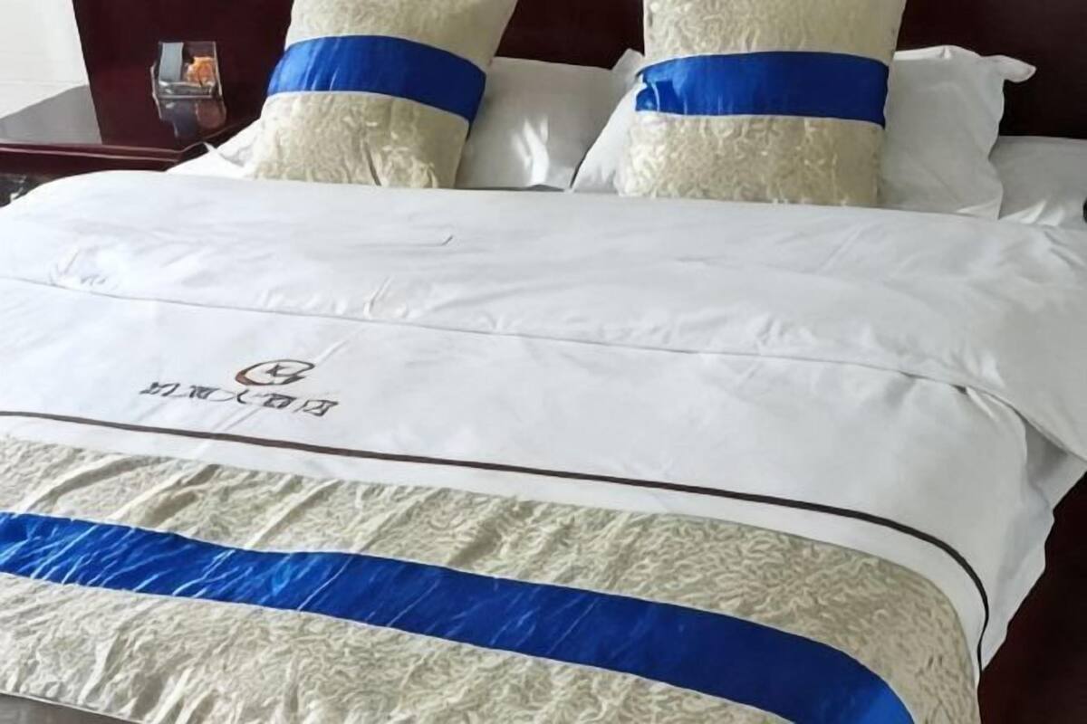 Ein Bett mit einer weißen und blauen Bettdecke, zwei Kissen und einem Logo auf der Decke.