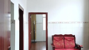 Ein Zimmer mit Holzstuhl, Spiegel und Fliesenwand.
