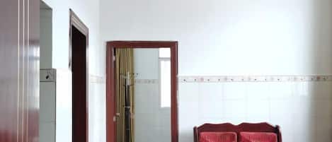 A room with a wooden chair, a mirror, and a tiled wall.