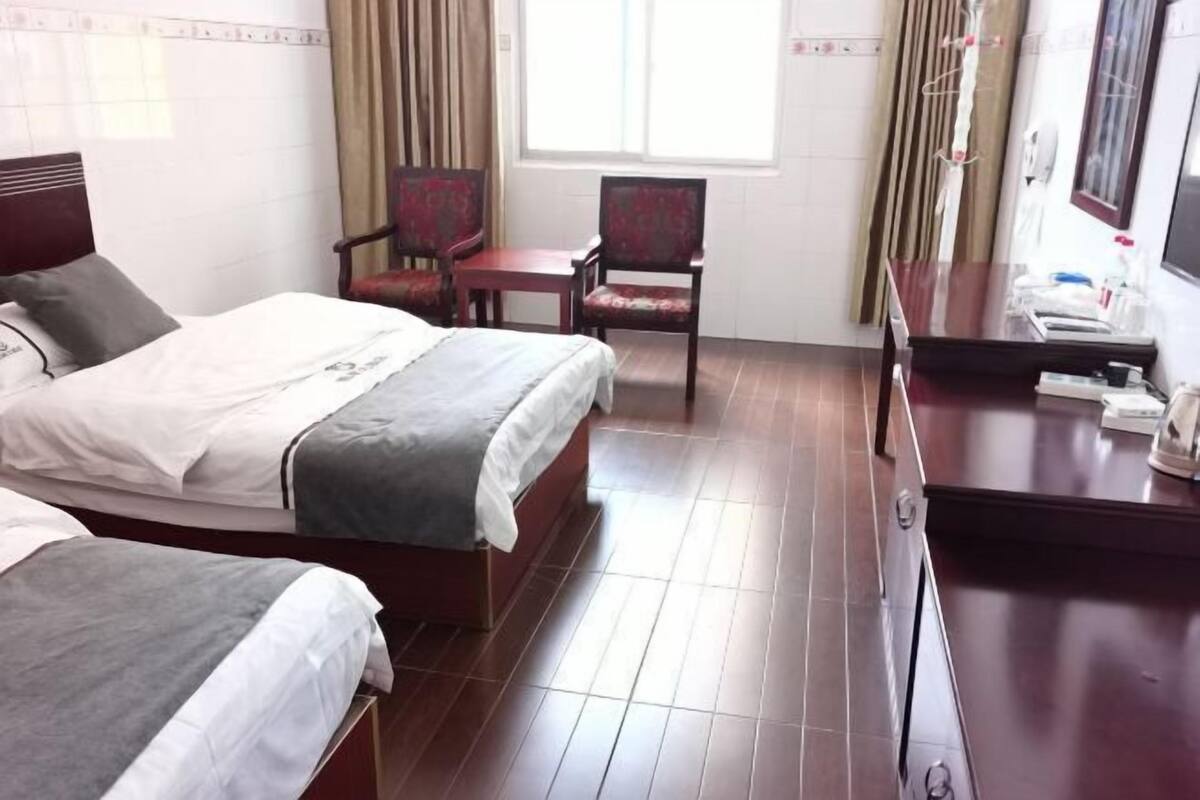 Ein Hotelzimmer mit zwei Betten, einem Schreibtisch und einem Stuhl.