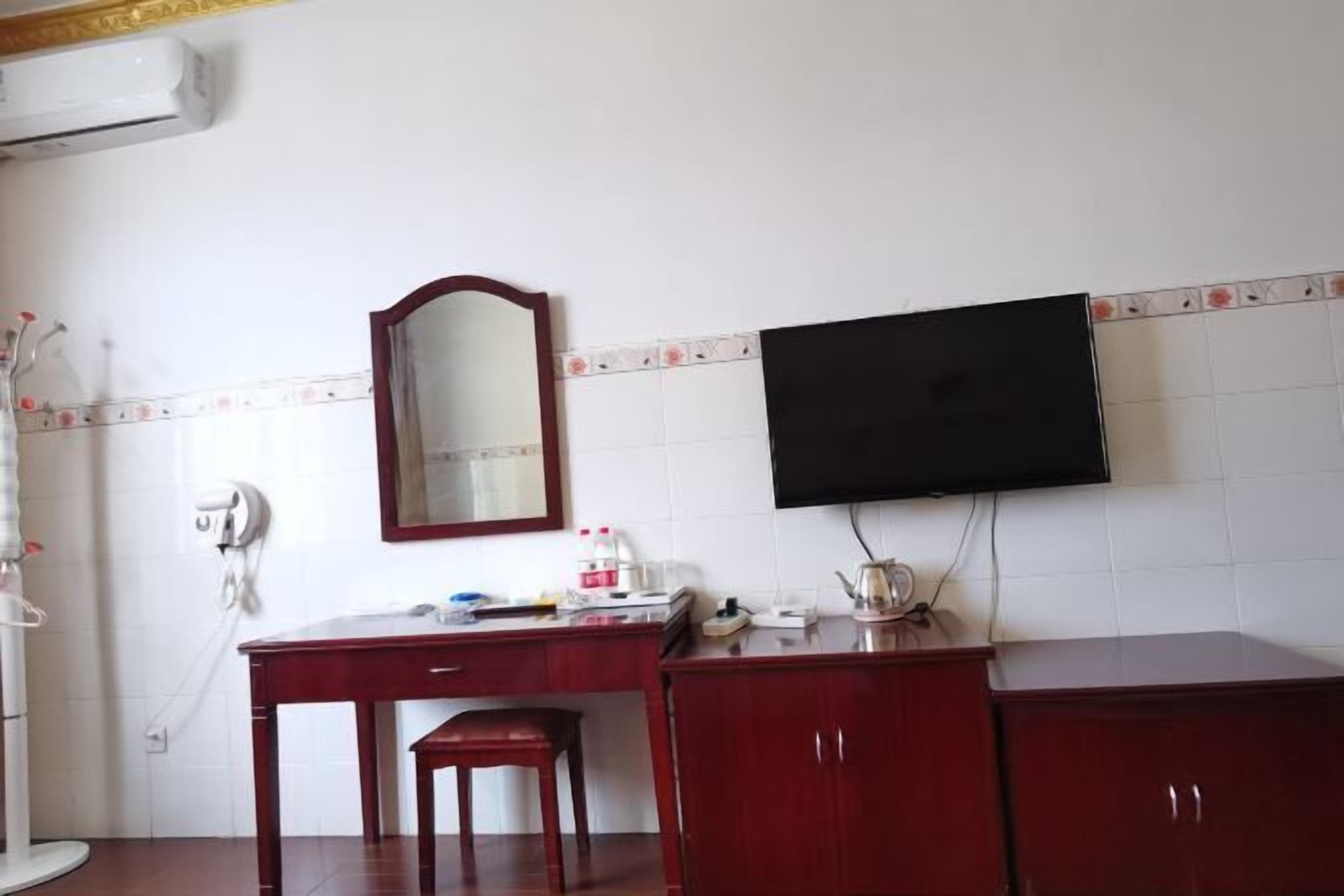 A room with a desk, a chair, a television mounted on the wall, and a mirror.