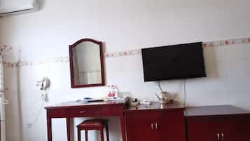 A room with a desk, a chair, a television mounted on the wall, and a mirror.