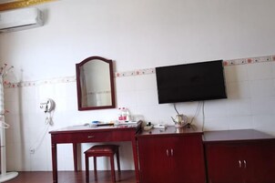 Una habitación con escritorio, silla, televisor en la pared y espejo.